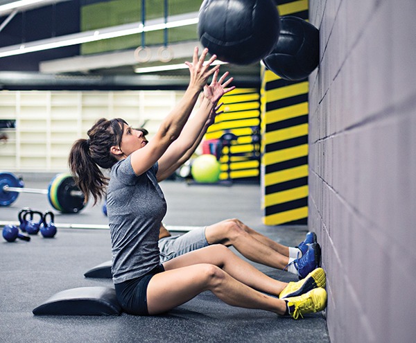 Woman throwing medicine ball against wall with TREAD Grip flooring